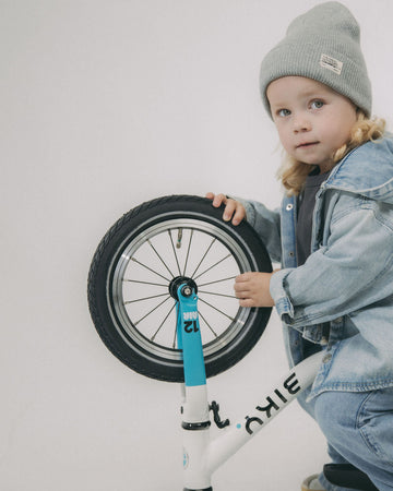 Child checking the front tire of a Biky Air 12 balance bike