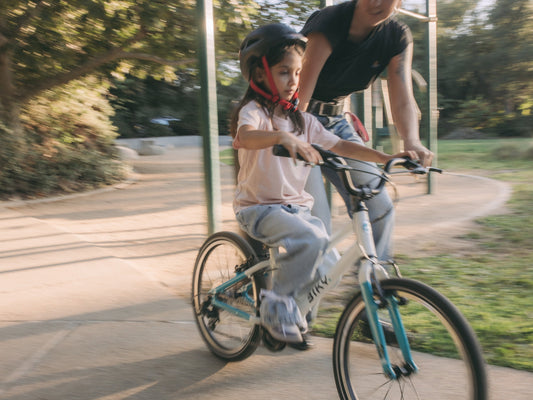 Child transitioning to a pedal bike without training wheels with adult support